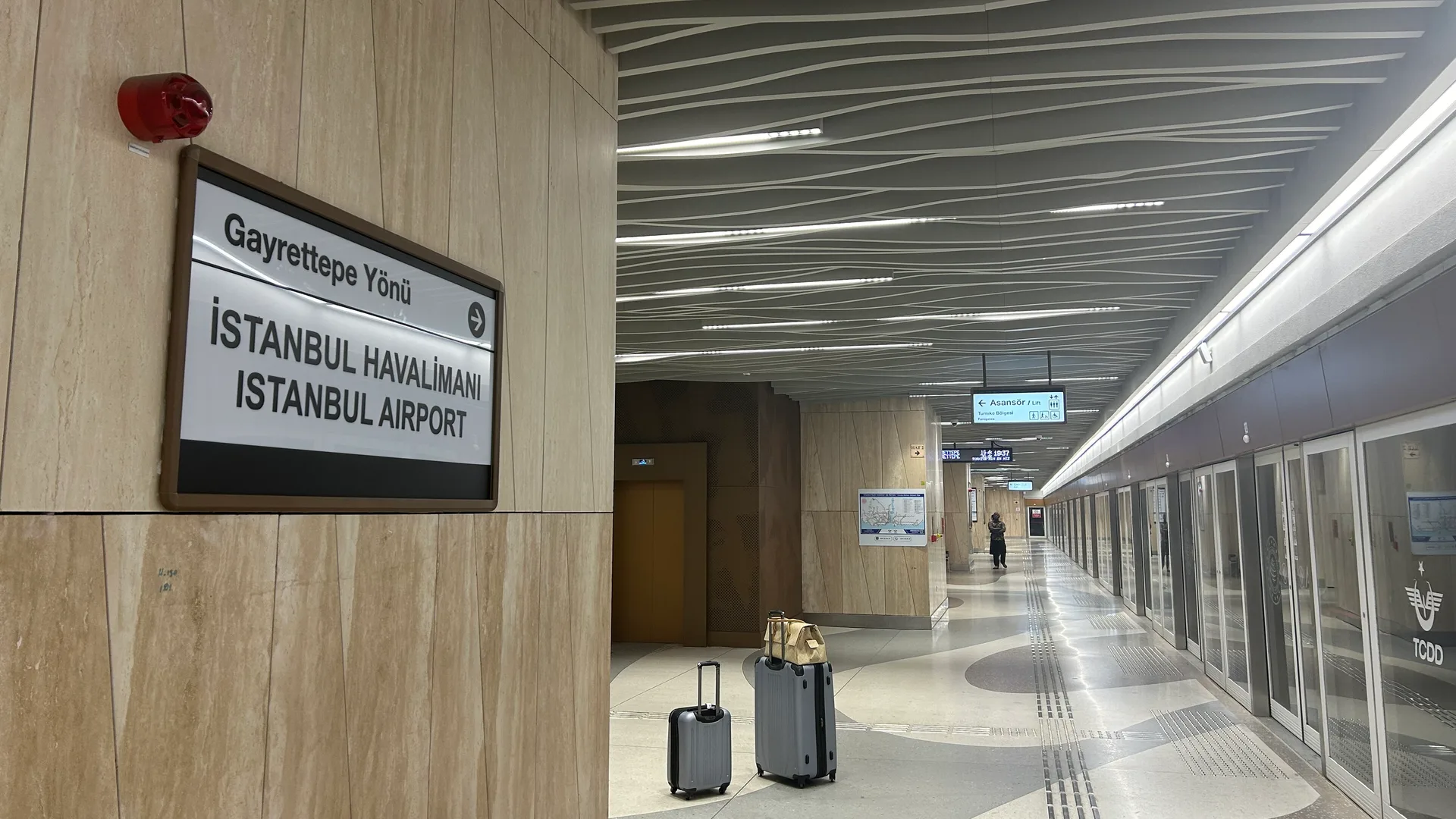 Metro peronunda İstanbul Havalimanı yön tabelası, dalgalı tavan ve yerde duran bavullar