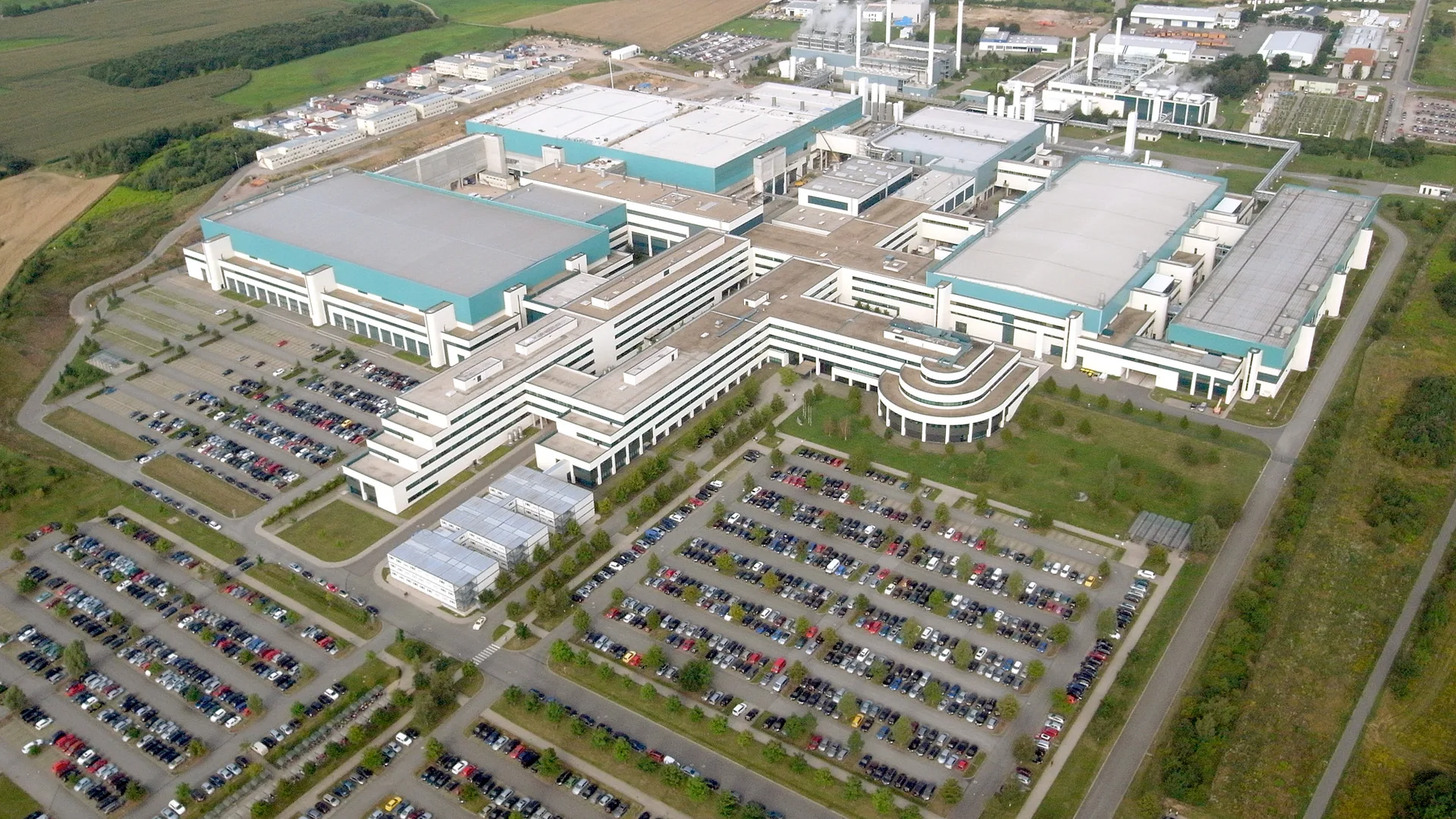Otoparklarla çevrili büyük bir fabrika kompleksinin havadan görüntüsü
