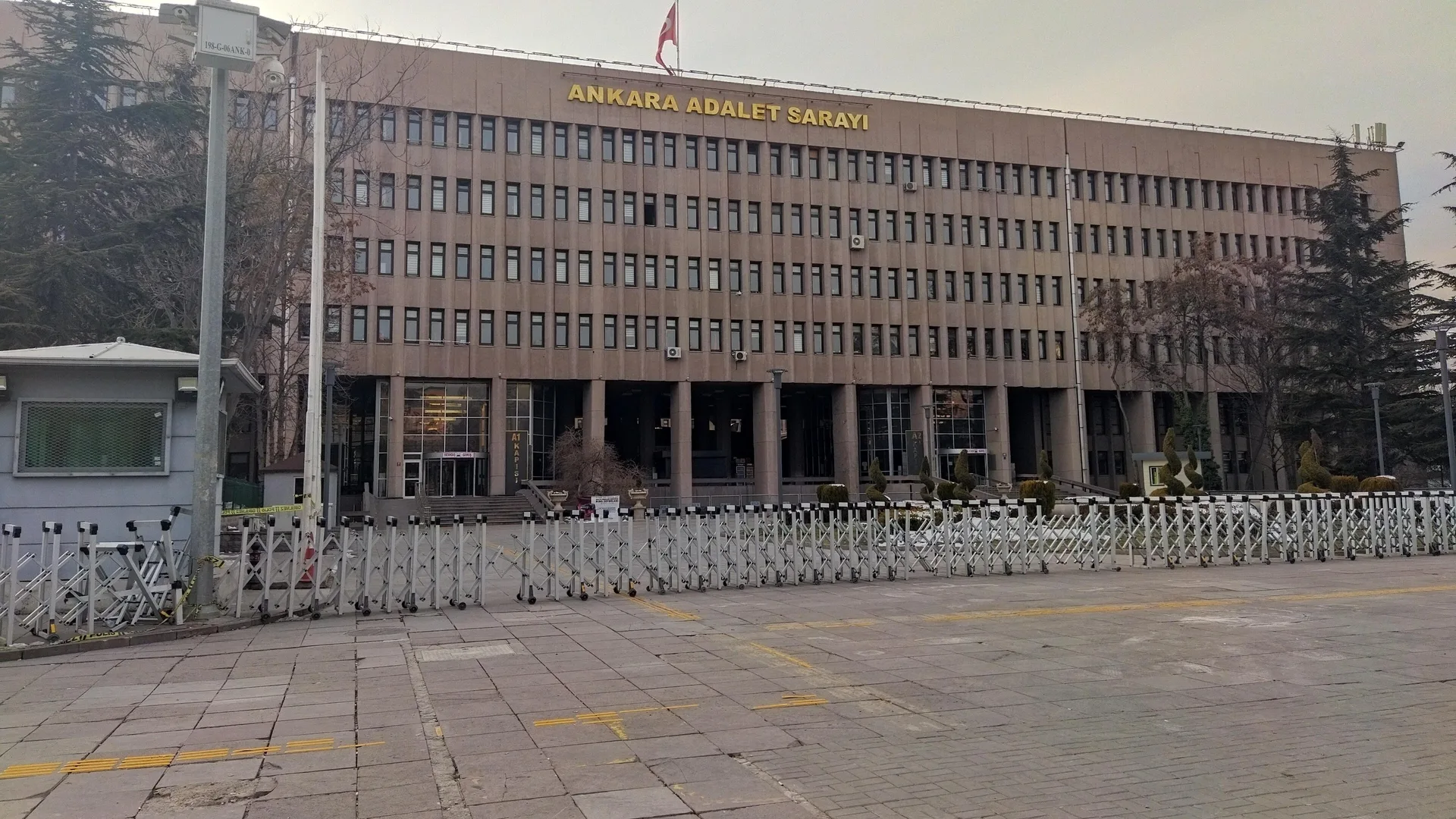 Önünde bariyerler bulunan, cephesinde Ankara Adalet Sarayı yazan çok katlı bina