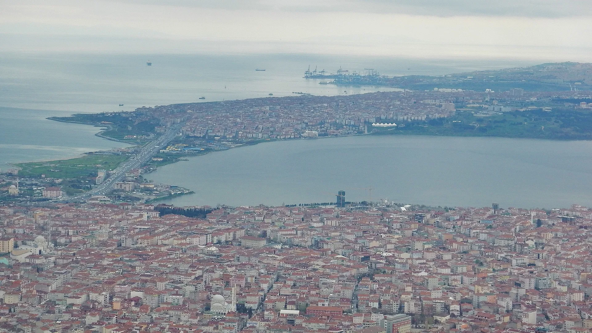 Göl kıyısındaki yoğun yerleşim ve uzakta denize uzanan şehrin havadan görünümü