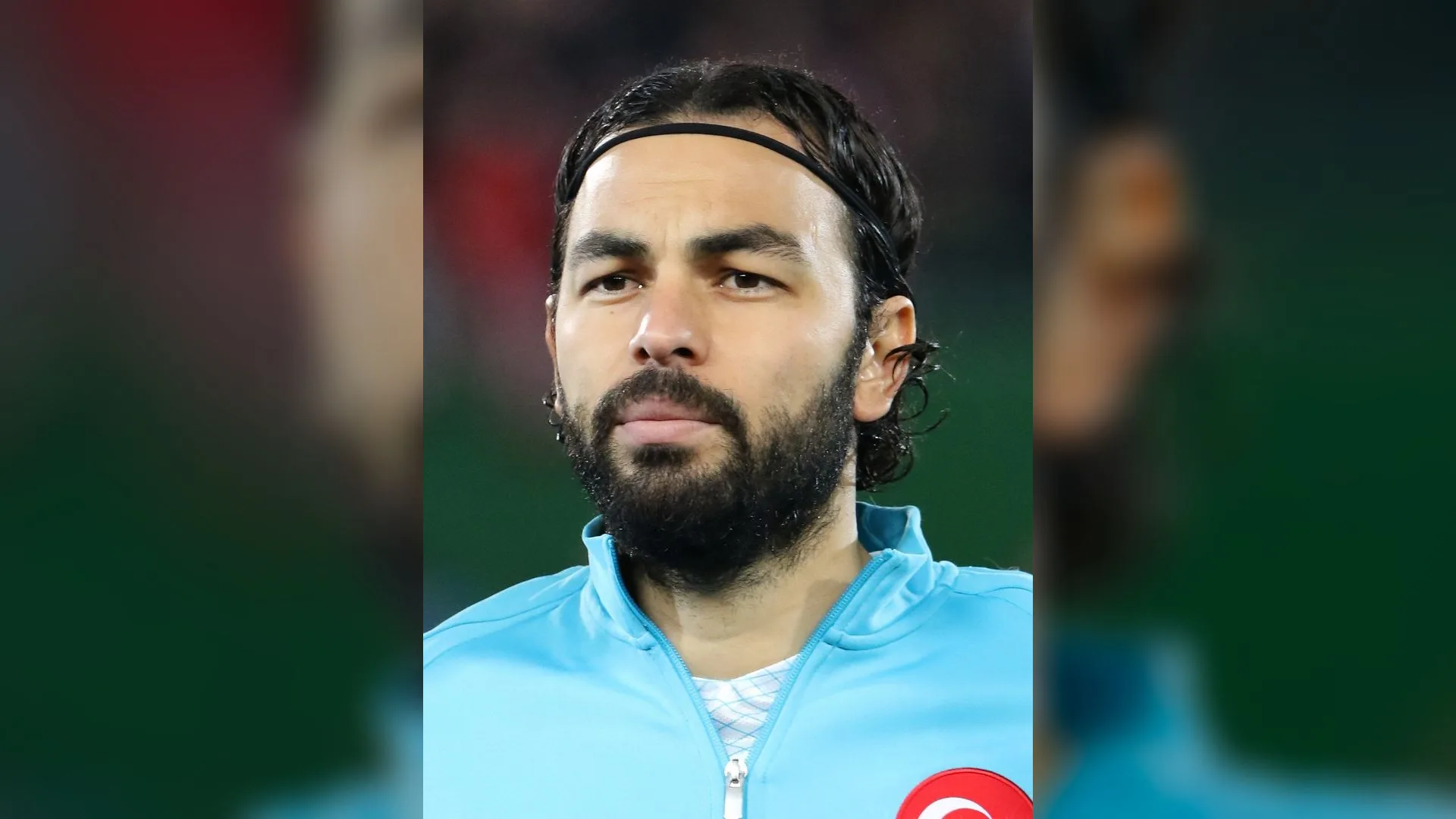 Turkuaz milli takım eşofmanlı, saç bantlı, sakallı bir futbolcunun portresi