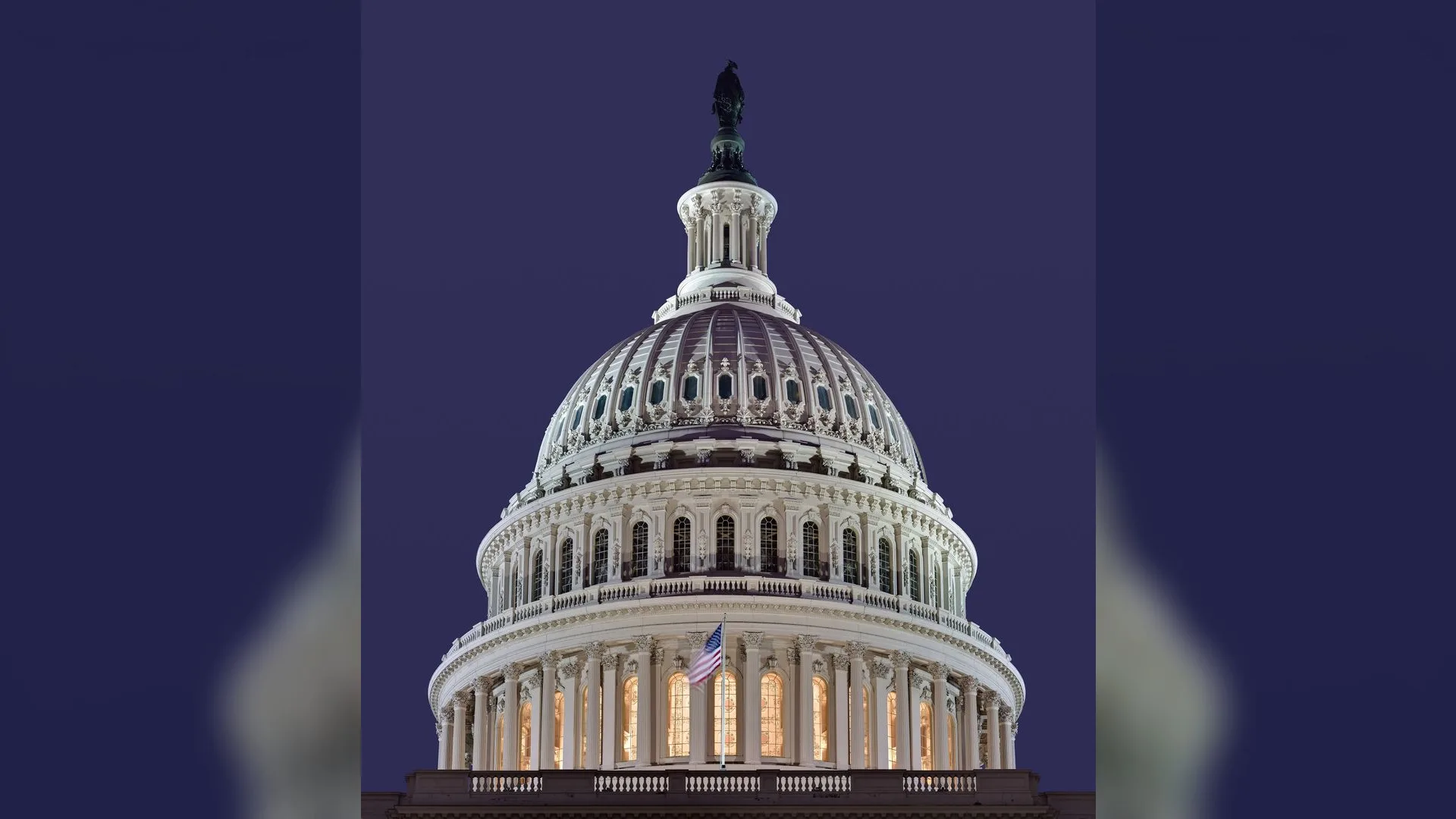 Gece mor gökyüzü altında ışıklandırılmış ABD Kongre Binası kubbesi ve dalgalanan Amerikan bayrağı