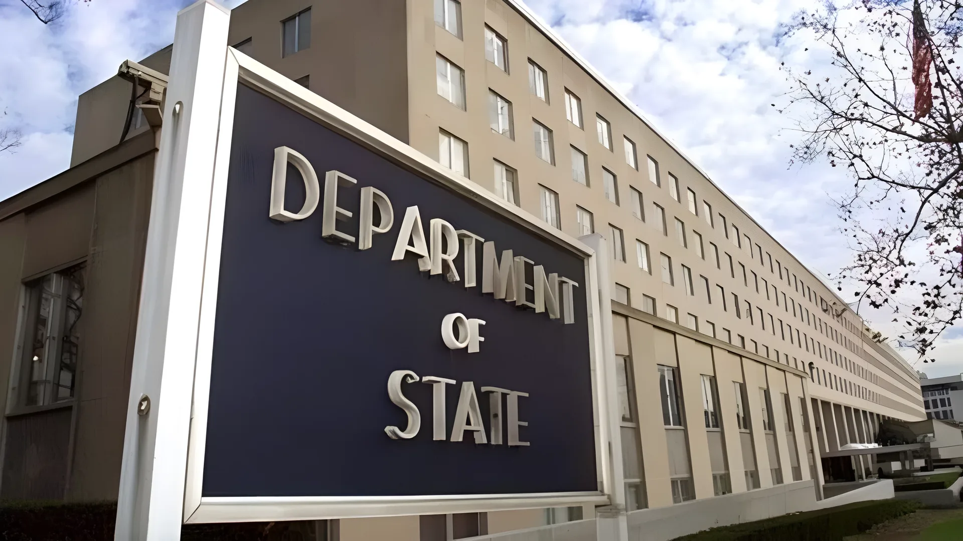 Önünde "Department of State" yazılı lacivert tabela bulunan çok katlı bej renkli bina