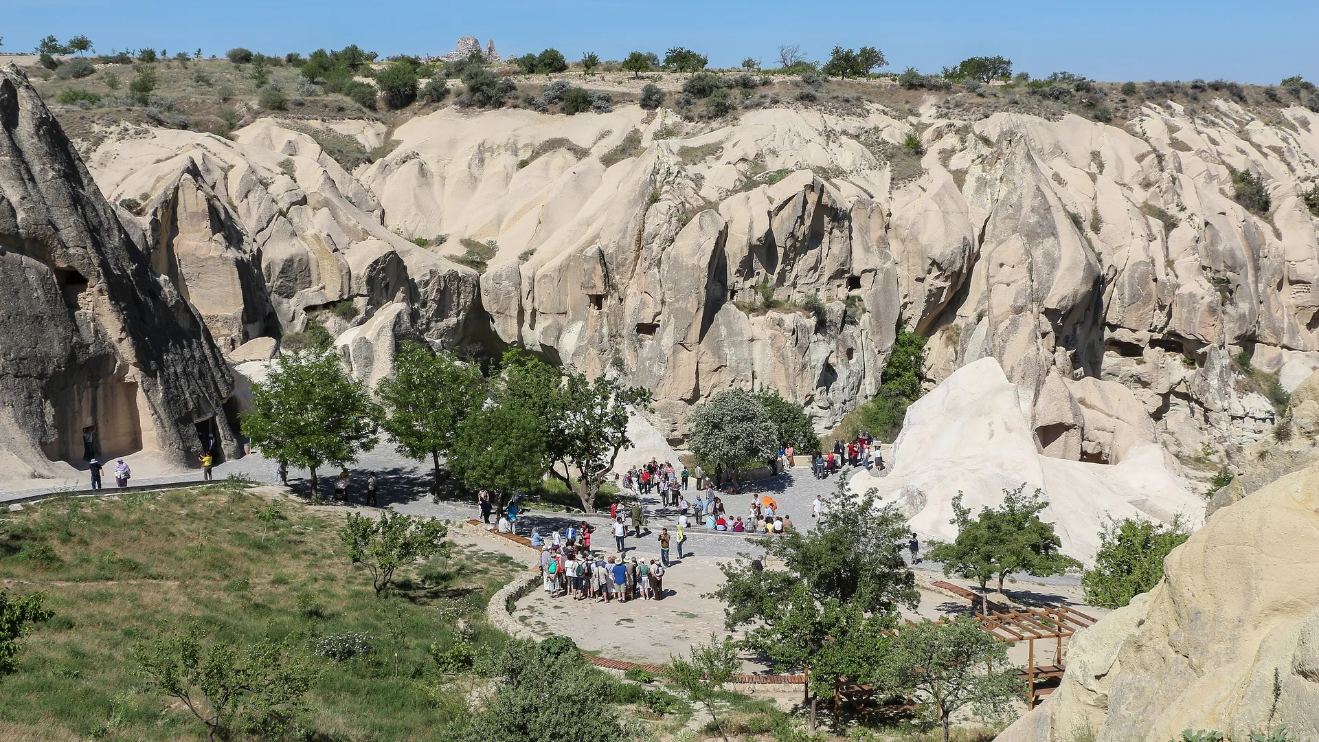 Kayalık vadide peribacalarının önünde toplanmış turist grupları