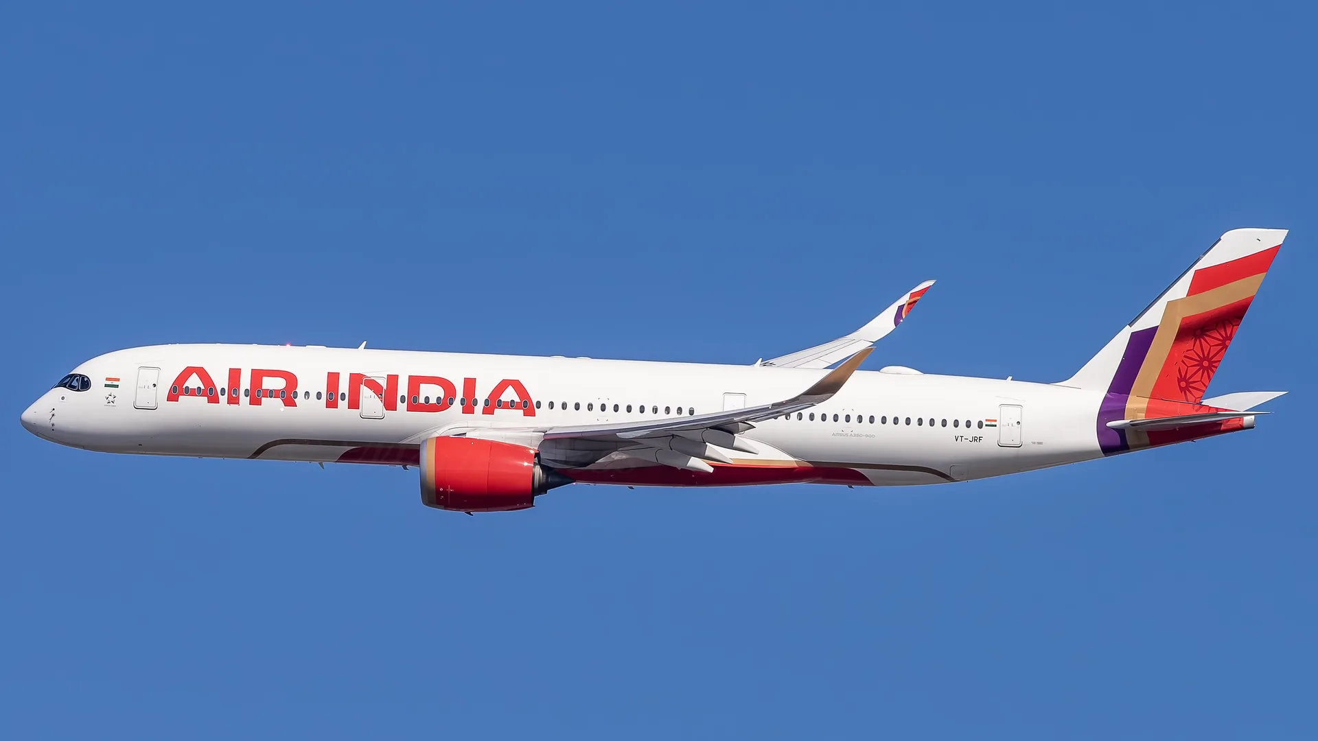 Mavi gökyüzünde uçan, kırmızı Air India yazılı beyaz yolcu uçağı