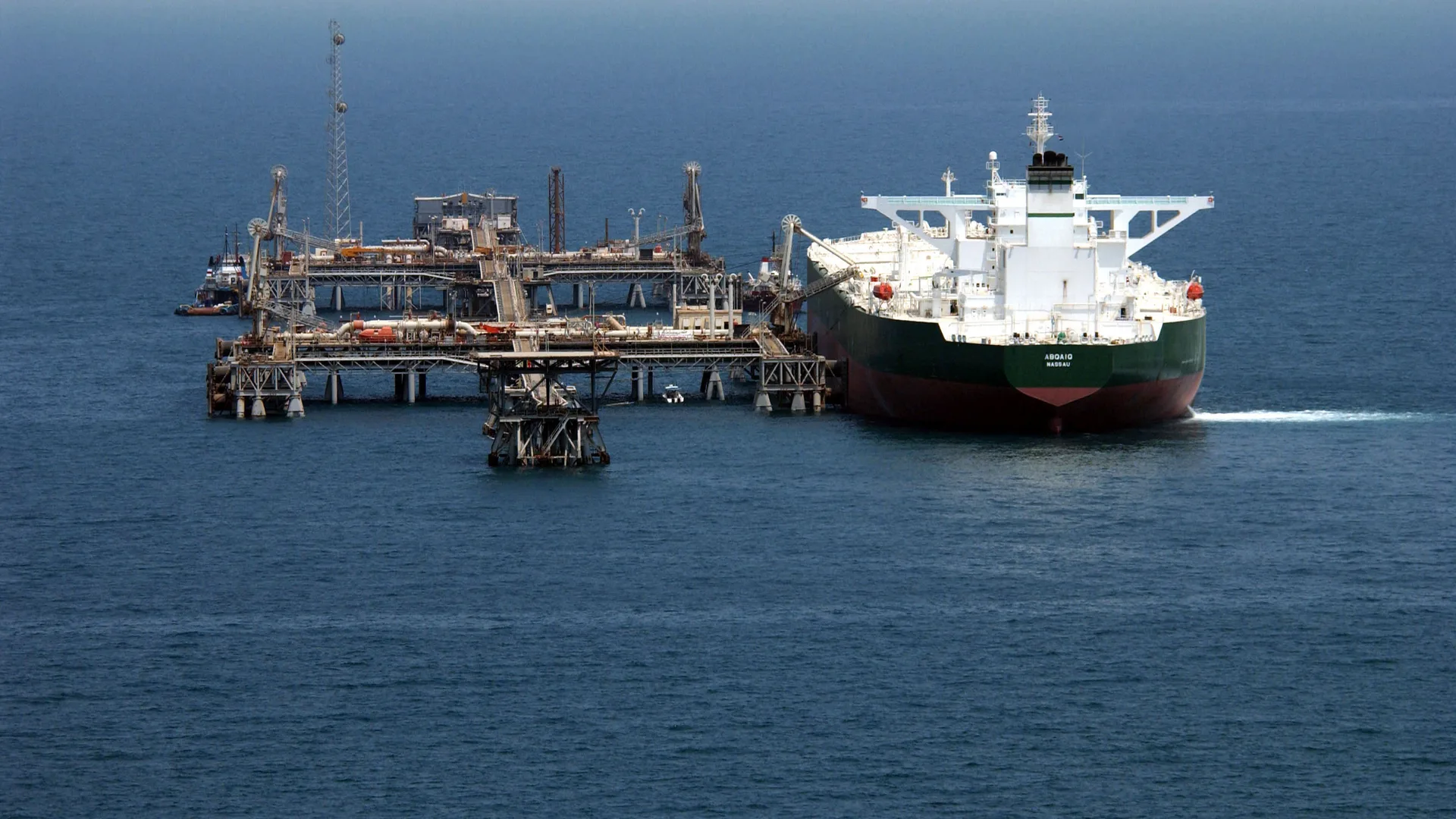 Açık denizde platform iskelesine yanaşmış büyük yeşil gövdeli petrol tankeri