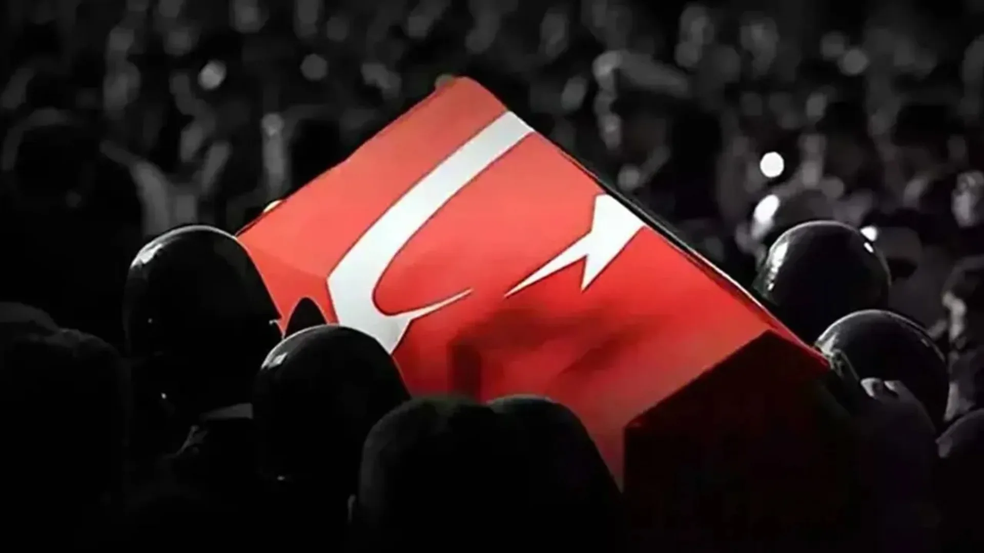 Siyah beyaz kalabalık içinde askerlerin omzunda taşınan Türk bayrağına sarılı tabut