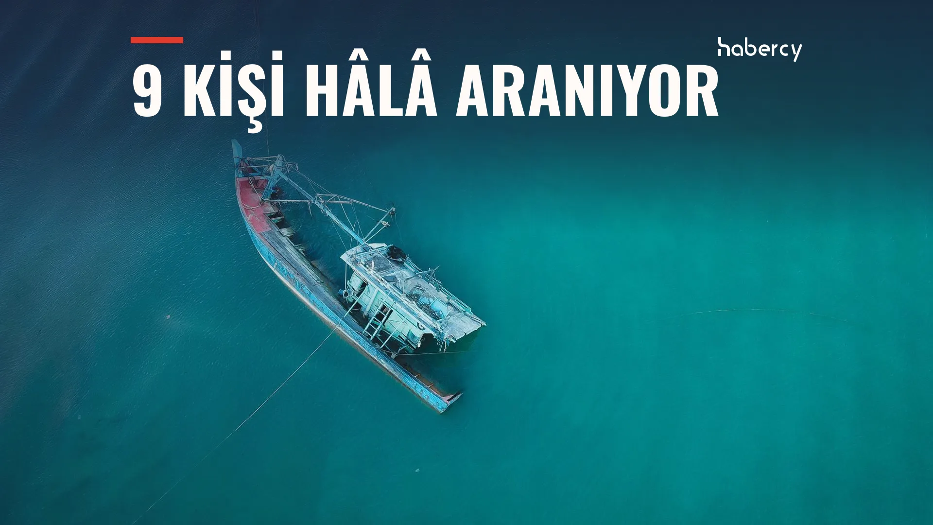 Turkuaz denizde yan yatmış, yarı batık bir balıkçı teknesinin havadan görünümü