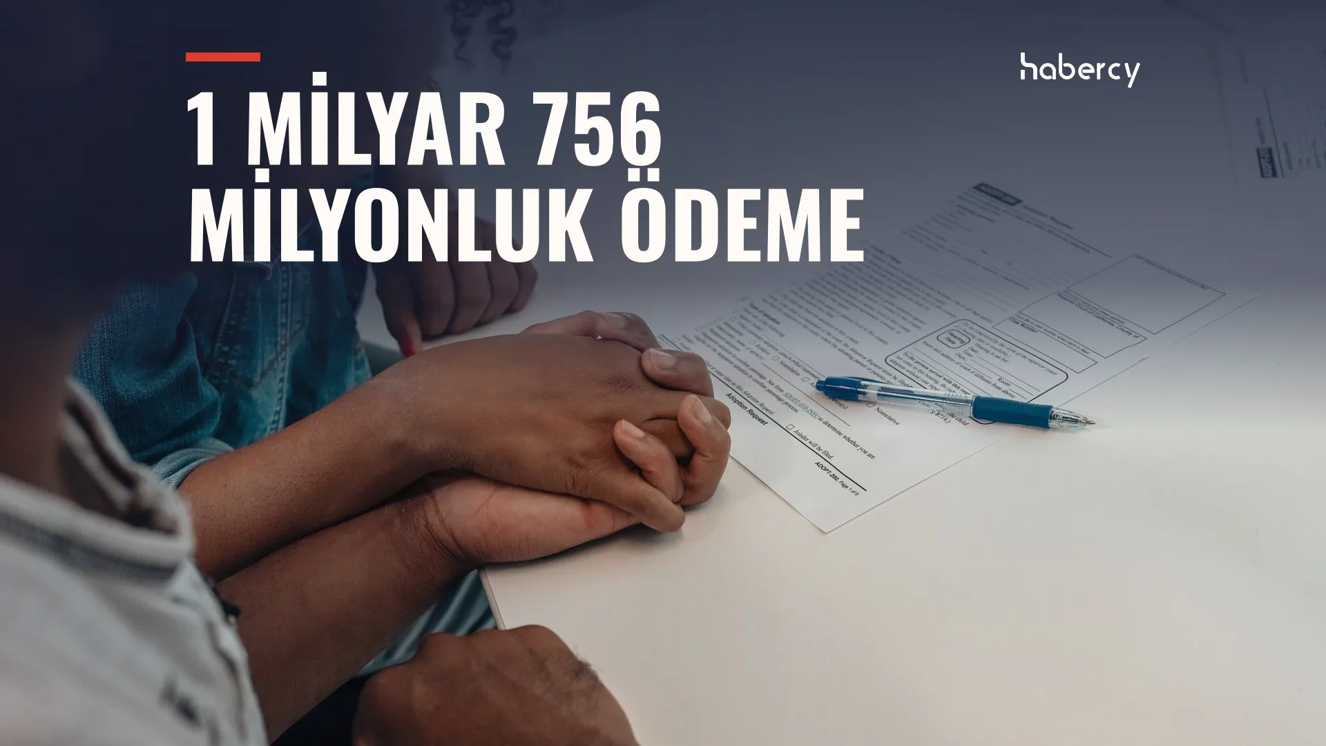 Masada form belgesi ve kalem yanında birbirinin elini tutan iki kişi