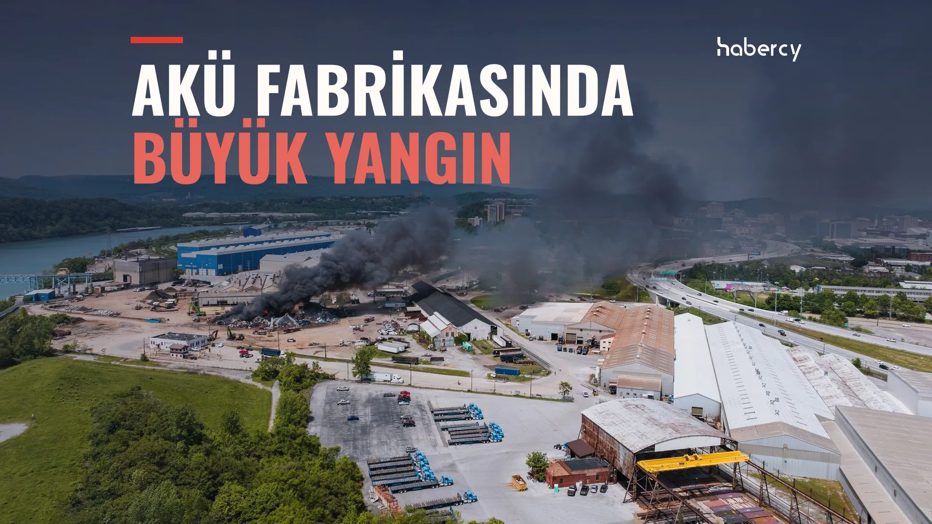 Nehir kıyısındaki sanayi alanında yükselen kara duman, depolar ve otoyol, havadan görünüm