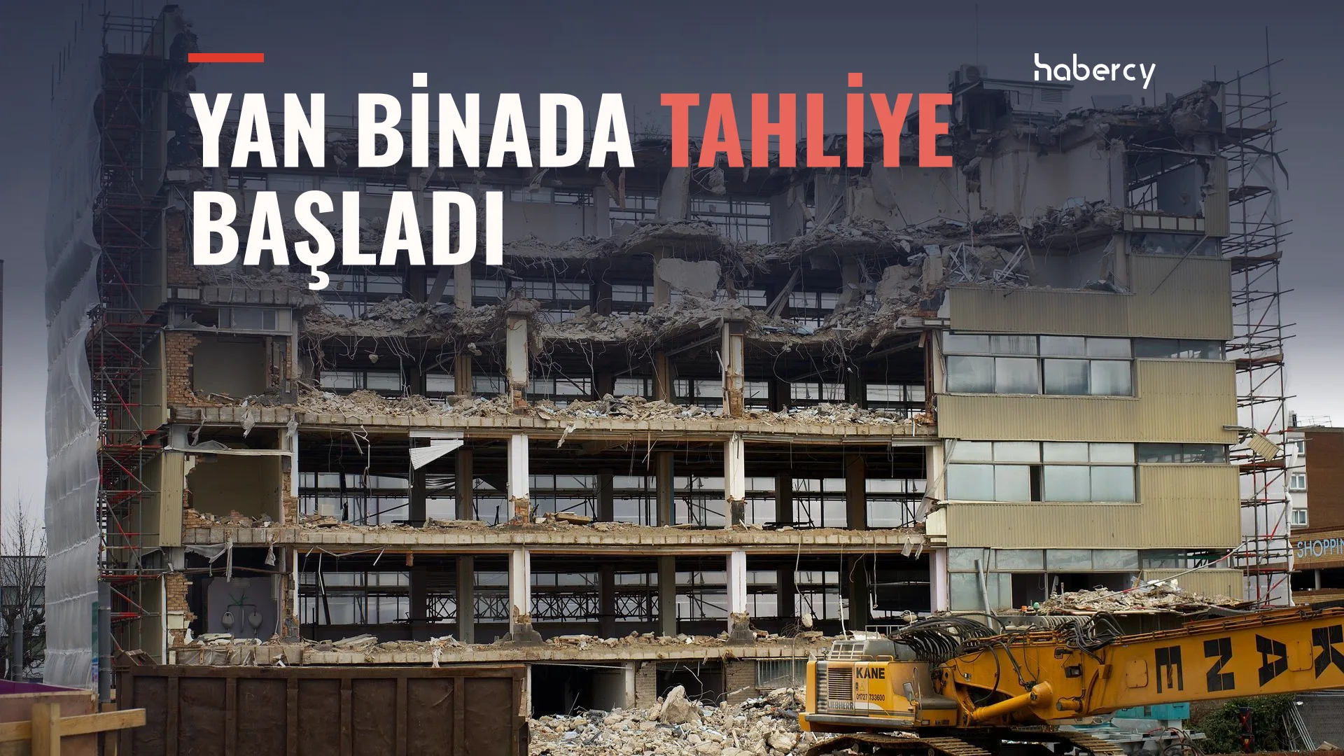 Yıkımı süren çok katlı beton binanın enkazı, önünde sarı bir iş makinesi ve iskeleler