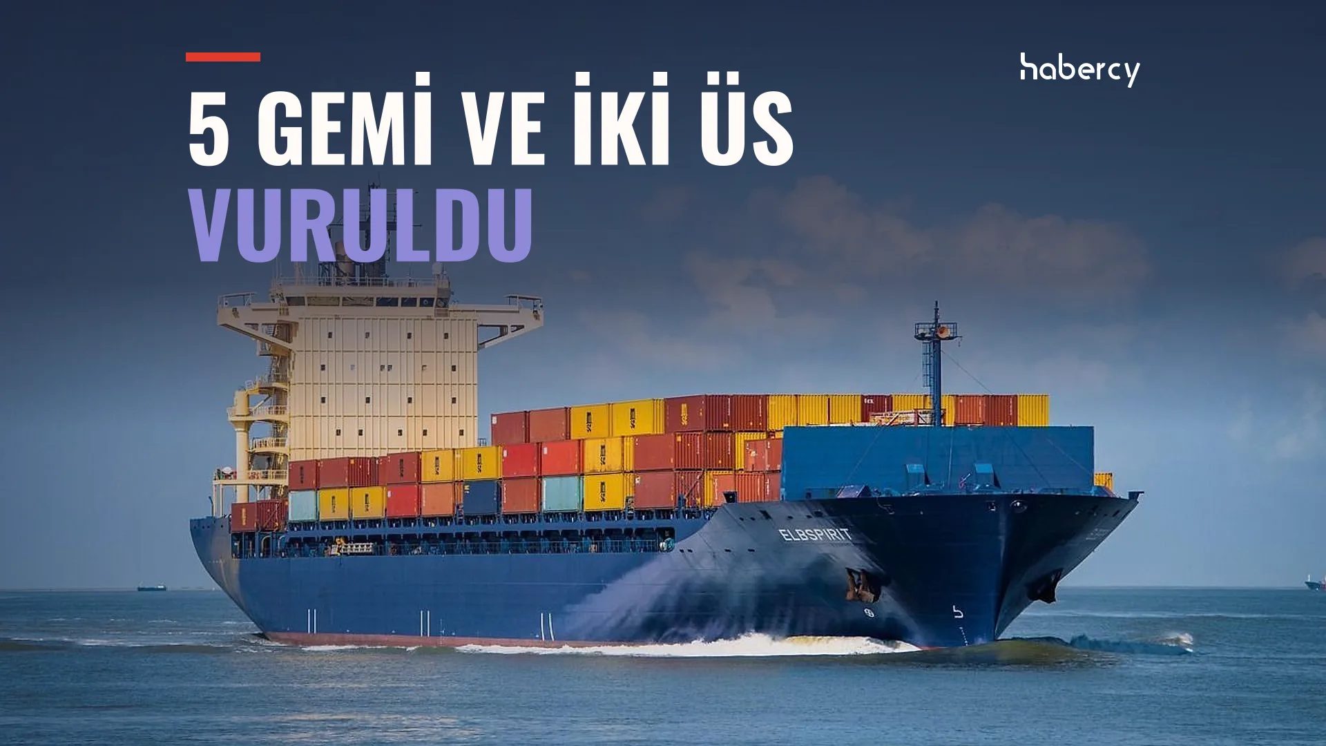Renkli konteynerlerle yüklü mavi gövdeli büyük bir yük gemisi denizde ilerliyor
