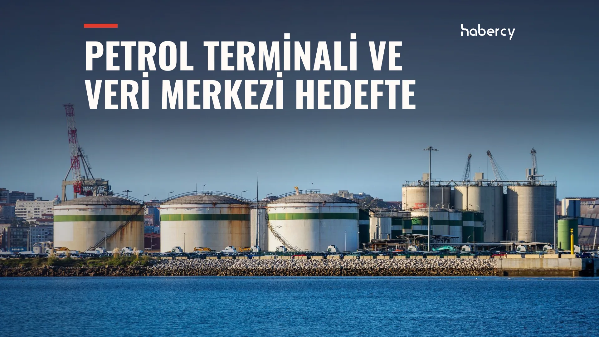 Deniz kıyısında beyaz-yeşil petrol depolama tankları ve vinçler
